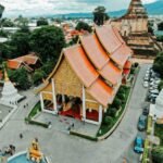 Aerial view of a temple complex in Chiang Mai surrounded by city streets, trees, and residential buildings.