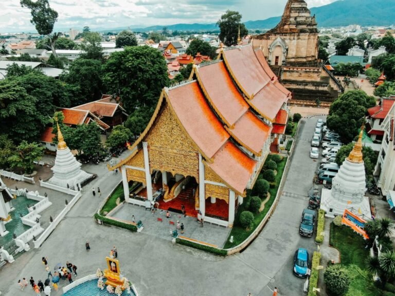 Aerial view of a temple complex in Chiang Mai surrounded by city streets, trees, and residential buildings.