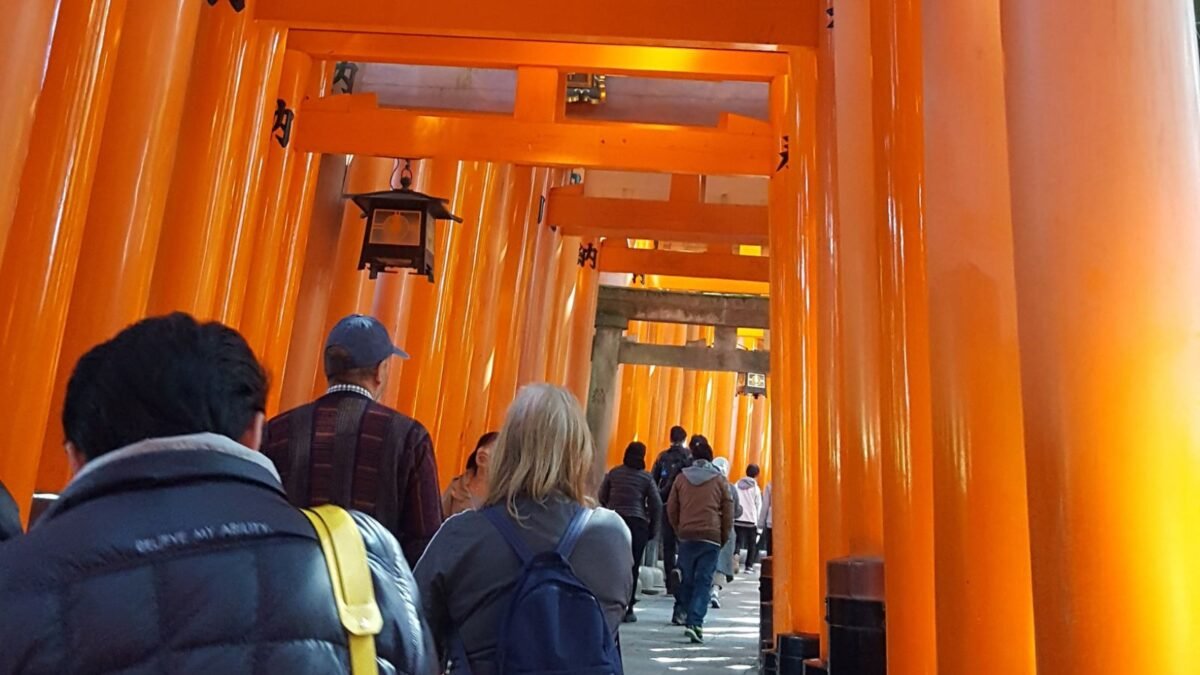 Visitors walking through red torii gates at Fushimi Inari Shrine Kyoto Japan