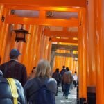 Visitors walking through red torii gates at Fushimi Inari Shrine Kyoto Japan