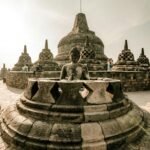 Borobudur Temple Buddha statue surrounded by stone stupas at sunrise, Central Java Indonesia