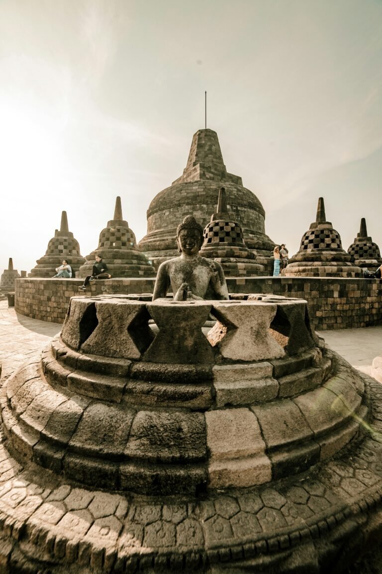 Borobudur Temple Buddha statue surrounded by stone stupas at sunrise, Central Java Indonesia