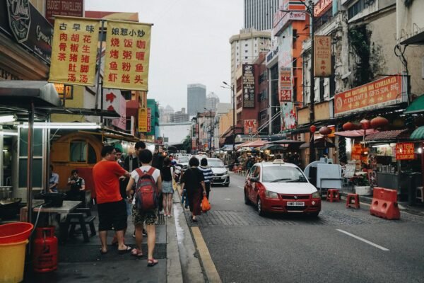 Petaling Street in Kuala Lumpur Chinatown with street food stalls, traffic, and busy sidewalks