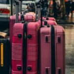 Multiple large suitcases standing on a rainy urban street during travel.