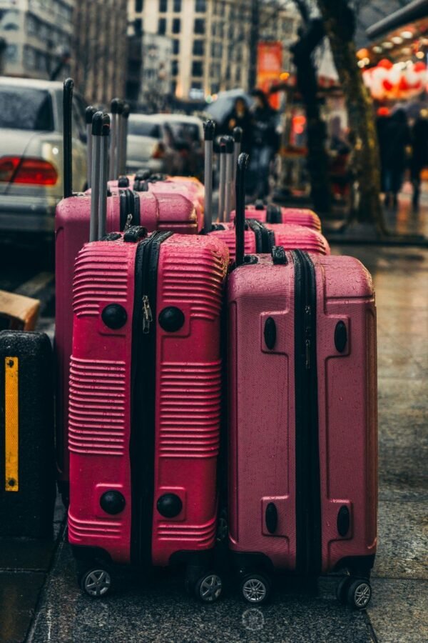 Multiple large suitcases standing on a rainy urban street during travel.