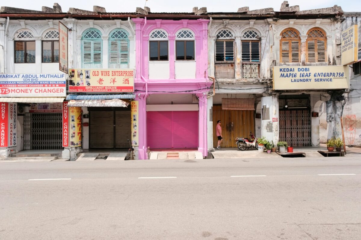 Row of weathered shophouses in George Town Penang with peeling paint and mixed signage