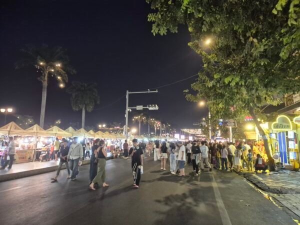 Crowds walking along Phnom Penh Riverside night market with food stalls and lights at night