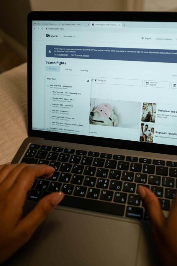 searching-flights-online-travel-planning Laptop showing flight search results while planning travel itinerary