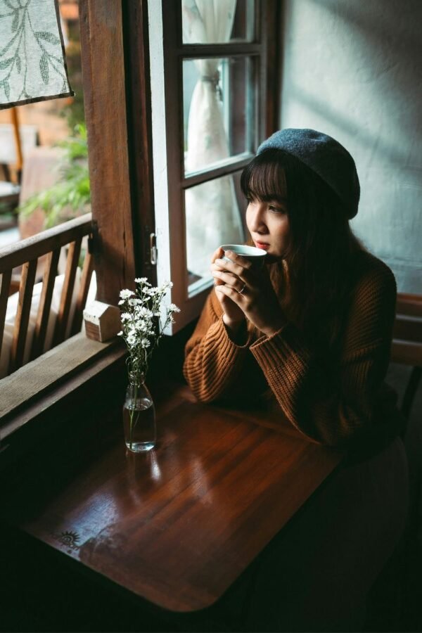 solo-traveler-cafe-reflective-moment Solo traveler sitting by a café window drinking tea and reflecting during a quiet moment of travel