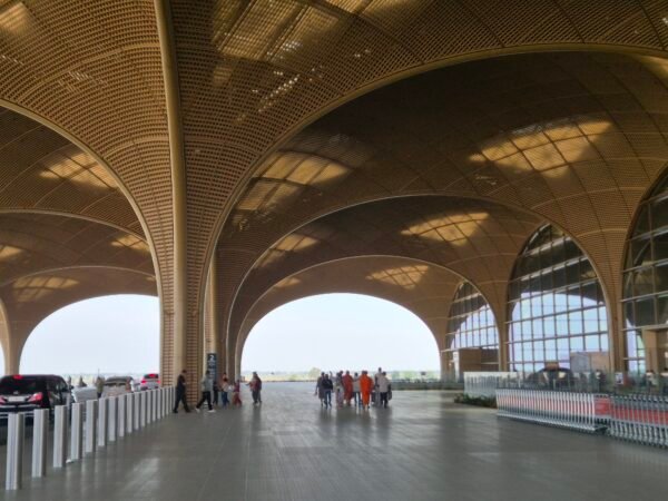 Exterior arrivals area of Techo International Airport Phnom Penh with large arched roof and passengers walking outside