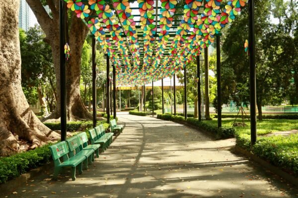 Tree-lined walkway with green benches at Benchasiri Park near Phrom Phong BTS in Bangkok