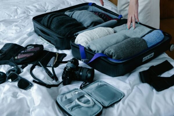Half-packed suitcase on a hotel bed with clothes and travel items laid out during a hotel change