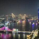 Da Nang skyline at night, with the pink cable-stayed Song Han Bridge in the foreground and the lit Dragon Bridge spanning the river beyond it