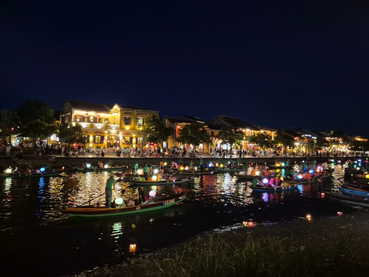 thu-bon-river-hoi-an-lanterns-boats Hoi An's old town riverfront at night, lantern-lit boats crowded on the water with the yellow French colonial shophouses glowing behind them