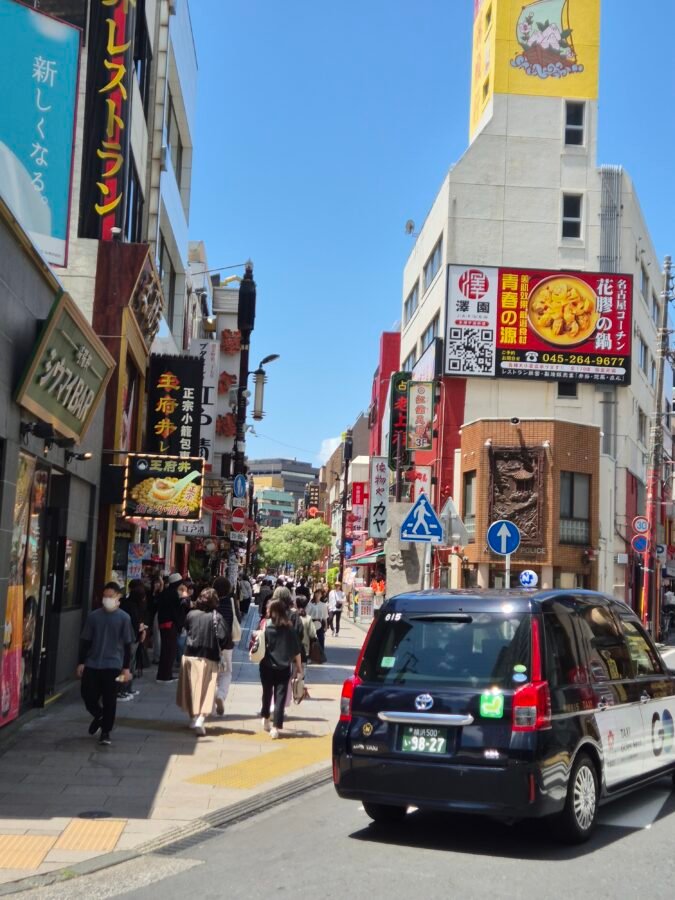 yokohama-chinatown-street-scene-tokyo-day-trip Busy street in Yokohama Chinatown lined with restaurant signage and a taxi passing through